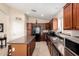 Galley kitchen with wooden cabinetry, black appliances, an island, and neutral countertops at 41847 W Sparks Ct, Maricopa, AZ 85138
