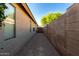 Narrow side yard with tan stucco wall and view of fence at 41847 W Sparks Ct, Maricopa, AZ 85138