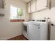 Laundry room with full size washer and dryer with a window that allows natural light and overhead cabinets for storage at 4527 E Sunrise Dr, Phoenix, AZ 85044