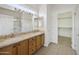Bathroom featuring double sinks, granite countertops, wood cabinets, and walk-in closet access at 6811 S Four Peaks Way, Chandler, AZ 85249