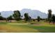 Scenic golf course view with lush green grass, mature trees, mountains, and a sand trap at 6811 S Four Peaks Way, Chandler, AZ 85249