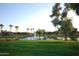 Scenic pond with a fountain surrounded by lush green grass, mature trees, and blue skies at 6811 S Four Peaks Way, Chandler, AZ 85249