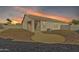 Backyard showing the house, gravel landscaping, and a beautiful sunset in the sky at 7580 W Darrel Rd, Laveen, AZ 85339