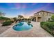 Beautiful backyard with a pool, spa, covered patio, and well-manicured landscaping at sunset at 9845 E Edgestone Dr, Scottsdale, AZ 85255
