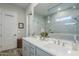 Bathroom with a dual sink vanity, framed mirror, and white tiled shower at 10509 W Harmony Ln, Peoria, AZ 85382