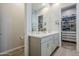 Bright bathroom featuring a double sink vanity, a large mirror, and a walk-in closet at 10509 W Harmony Ln, Peoria, AZ 85382
