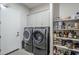 A modern laundry room featuring gray front load washer and dryer, storage cabinets, and shelving with necessities at 10509 W Harmony Ln, Peoria, AZ 85382