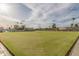 Expansive lawn bowling field with seating, palm trees, and well-maintained grounds under a partly cloudy sky at 10724 W Cheryl Dr, Sun City, AZ 85351