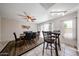 A dining room with a ceiling fan, tiled floors, and a dark wood table with chairs set on a decorative area rug at 10827 W Santa Fe Dr, Sun City, AZ 85351