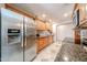 Bright kitchen with stainless steel refrigerator and appliances, warm wood cabinetry, and granite countertops at 10827 W Santa Fe Dr, Sun City, AZ 85351