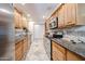 Spacious kitchen featuring stainless steel appliances, ample wooden cabinetry, tile backsplash, and granite countertops at 10827 W Santa Fe Dr, Sun City, AZ 85351