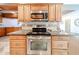 Close-up of the kitchen range with granite countertops, wooden cabinets, stainless steel appliances, and decorative backsplash at 10827 W Santa Fe Dr, Sun City, AZ 85351