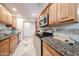 Well-lit kitchen equipped with stainless steel appliances, wood cabinets, granite counters, and a tile backsplash at 10827 W Santa Fe Dr, Sun City, AZ 85351