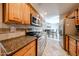 The kitchen features stainless steel appliances, wooden cabinetry, granite countertops, and stylish backsplash tiles at 10827 W Santa Fe Dr, Sun City, AZ 85351