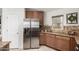 Kitchen featuring stainless steel refrigerator, wood cabinets, granite counters, and tile floors at 11402 W Hadley St, Avondale, AZ 85323