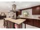 Spacious kitchen with an island cooktop, marble countertop, dark cabinets, and wine refrigerator at 12423 N 64Th St, Scottsdale, AZ 85254