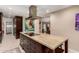 Elegant kitchen island with a cooktop, marble countertop, dark cabinetry, and stylish decor at 12423 N 64Th St, Scottsdale, AZ 85254