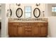 Bathroom featuring & sinks, framed mirrors, and wood cabinets with stylish hardware at 17665 N 93Rd Way, Scottsdale, AZ 85255