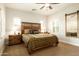 Bright main bedroom featuring a decorative wood headboard, a ceiling fan, plantation shutters, and a full-length mirror at 17665 N 93Rd Way, Scottsdale, AZ 85255