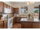 Functional kitchen with wooden cabinets, island, white appliances and lots of light from the window above the sink at 18222 W Lundberg St, Surprise, AZ 85388