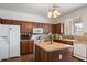 Functional kitchen with wooden cabinets, island, white appliances and lots of light from the window above the sink at 18222 W Lundberg St, Surprise, AZ 85388