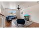 Bright living room featuring a comfortable blue sofa, ceiling fan, and large window that fills the room with natural light at 18222 W Lundberg St, Surprise, AZ 85388