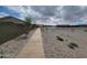 A long sidewalk is surrounded by rocks and very little plant life as it winds through the community at 19390 N Fiano Dr, Maricopa, AZ 85138