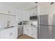 A well-lit kitchen featuring stainless steel appliances, white cabinets with brass hardware, and ample counter space at 2033 E Janice Way, Phoenix, AZ 85022