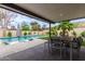 The outdoor patio features a shaded seating area, backyard pool, and surrounding landscaping at 2033 E Janice Way, Phoenix, AZ 85022