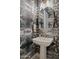 Stylish powder room featuring a geometric mirror, white pedestal sink, and unique patterned wallpaper at 20797 W Rattler Rd, Buckeye, AZ 85396