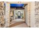 Covered entry showcasing stone pillar accents, a brick-paved walkway, and a welcoming front door with sidelights at 20797 W Rattler Rd, Buckeye, AZ 85396