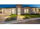 Charming stone home featuring an attached garage and lush front yard landscaping, all beautifully illuminated at twilight at 20797 W Rattler Rd, Buckeye, AZ 85396