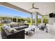 Covered patio offers stylish outdoor seating with a fan, overlooking the landscaped backyard at 20797 W Rattler Rd, Buckeye, AZ 85396
