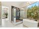 Bright bathroom featuring a glass enclosed shower, soaking tub, and backyard views at 21240 N 74Th Pl, Scottsdale, AZ 85255