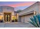 Front entry of a home, highlighting a well-lit entryway with a concrete driveway and desert landscaping at 21240 N 74Th Pl, Scottsdale, AZ 85255