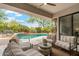 Covered patio with comfortable seating overlooking a lush, landscaped pool area with rock waterfall at 21240 N 74Th Pl, Scottsdale, AZ 85255
