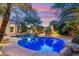 Backyard pool with rock waterfall and mature landscaping, illuminated at twilight for a relaxing ambiance at 21240 N 74Th Pl, Scottsdale, AZ 85255