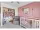 Bright Bedroom featuring pink wall, a crib, a rocking chair, and a closet full of organized clothes at 2150 W Alameda Rd # 1313, Phoenix, AZ 85085