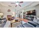 Spacious living room featuring hardwood floors, a ceiling fan, and comfortable seating options with a modern TV setup at 21968 W Hadley St, Buckeye, AZ 85326