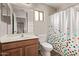 Bathroom features a sink with wooden cabinet and a colorful shower curtain at 2438 W Via Dona Rd, Phoenix, AZ 85085