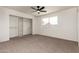 Well-lit bedroom with neutral carpeting, a ceiling fan, and a closet with built-in shelving at 2551 E Harmony Ave, Mesa, AZ 85204