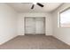 Carpeted bedroom with ceiling fan, window, and large closet with built-in shelves at 2551 E Harmony Ave, Mesa, AZ 85204
