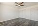 A spacious bedroom featuring new grey wood floors, a ceiling fan, and closet with sliding doors at 3017 N 46Th Dr, Phoenix, AZ 85031