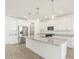 An open kitchen has a large island, granite counters, a stainless steel refrigerator and microwave, and pendant lighting at 37114 W La Paz St, Maricopa, AZ 85138
