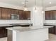 Kitchen with dark wood cabinetry, granite countertops, stainless appliances and island pendant lighting at 37371 W San Sisto Ave, Maricopa, AZ 85138