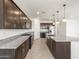 Modern kitchen with granite countertops, stainless appliances, large island, dark wood cabinetry, and tile floors at 37371 W San Sisto Ave, Maricopa, AZ 85138
