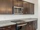 Close up on new kitchen appliances with granite countertops and dark wood cabinetry at 37371 W San Sisto Ave, Maricopa, AZ 85138