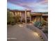Desert home features an inviting entrance, desert landscaping, stone accents, and lit circular driveway at 39602 N Charles Blair Macdonald Rd, Scottsdale, AZ 85262
