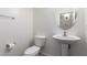 Simple half bath with pedestal sink, toilet, and round mirror at 43228 W Knauss Dr, Maricopa, AZ 85138