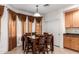 Dining area boasts a wooden table with chairs, complemented by elegant drapery and natural light, adjacent to kitchen at 43228 W Knauss Dr, Maricopa, AZ 85138